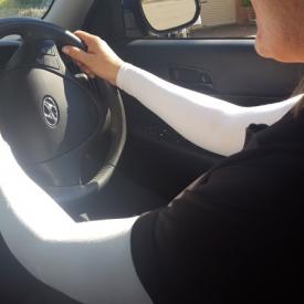 A woman driving a car and wearing IceRays Sun Sleeves for sun protection from harmful UV rays while driving. Driving 