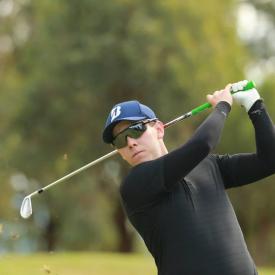 A man finishing his golf swing and wearing black IceRays Sun Sleeves to match his shirt and to protect his arms from the sun while golfing. Sun Protection! Golf 