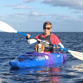 A woman kayaking with her dog and wearing IceRays Sun Sleeves for Maximum UV sun protection while paddling on the water. Kayaking 